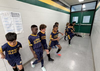 Young basketball players sitting on a bench in a gym hallway.