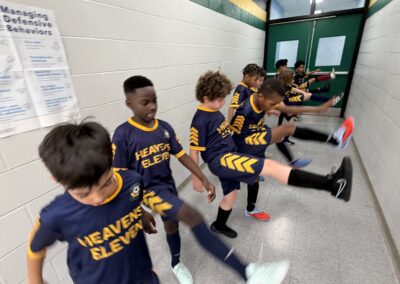 Children in matching sports jerseys stretch together in a gym.