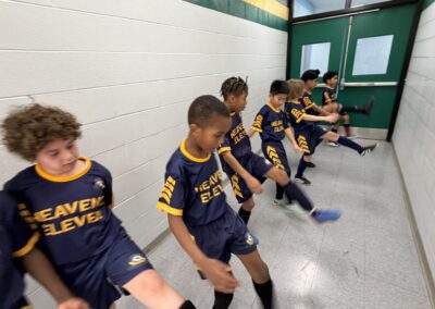 Young boys in matching soccer jerseys sitting on a bench indoors.