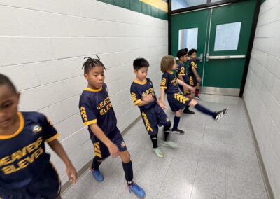 Young basketball players in uniforms sitting on a bench indoors.