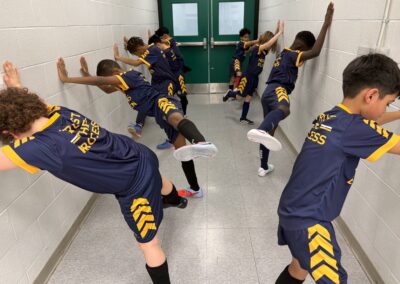 A group of students in uniforms posing energetically in a hallway.
