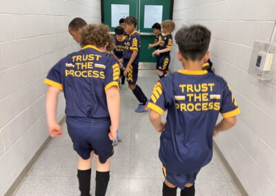 Youth soccer players walking down a hallway in matching uniforms.