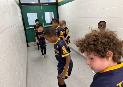Young boys in sports uniforms lined up in a hallway.