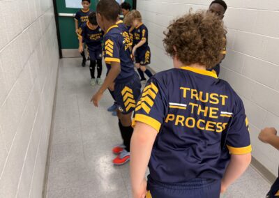 Children in matching sports jerseys playing a hallway game.