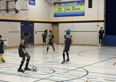 Young boys playing indoor soccer in a gymnasium.