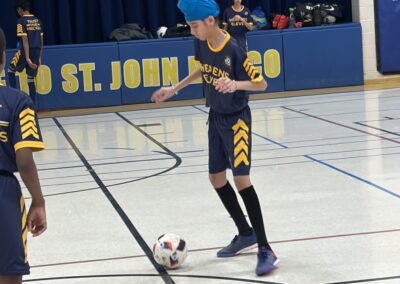 Young boy in blue sportswear playing indoor soccer.