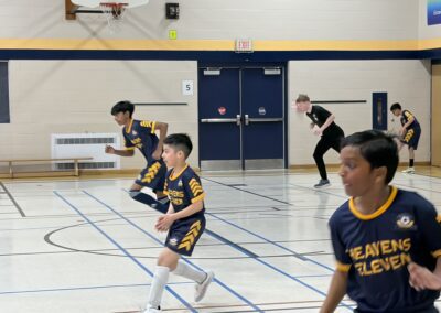 Youth basketball players ready in defensive stance on indoor court.