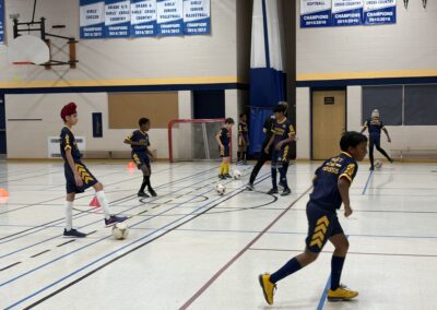Children playing indoor soccer in a gymnasium.