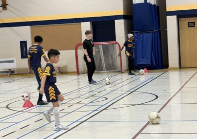 Children playing indoor soccer in a gymnasium.