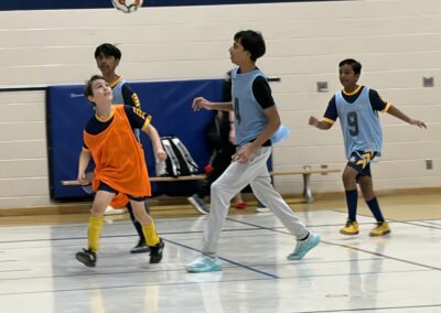 Kids playing indoor soccer in a gymnasium.