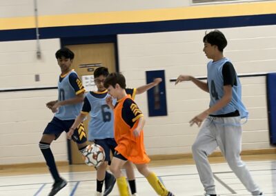 Young boys playing indoor soccer, competing for the ball.
