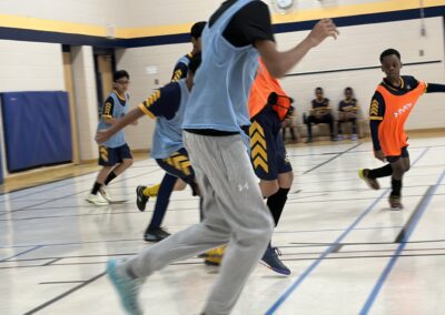 Players in blue and orange jerseys compete in an indoor basketball game.
