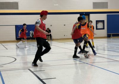 Kids playing indoor floor hockey with enthusiasm in a gym.