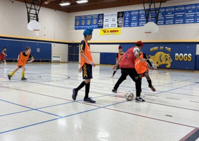 Young boys playing basketball indoors in a gymnasium.