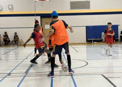 Children playing indoor soccer in a gymnasium.