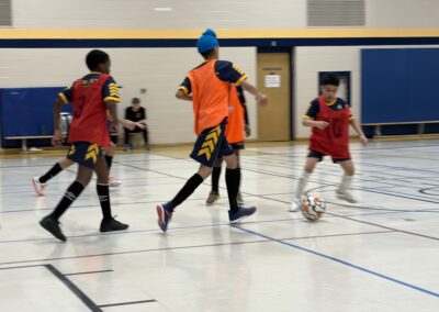 Children playing indoor soccer in a gymnasium.