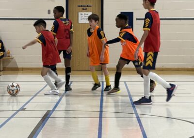 Kids playing basketball, practicing dribbling skills indoors.