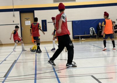 Children playing indoor soccer in a gymnasium.