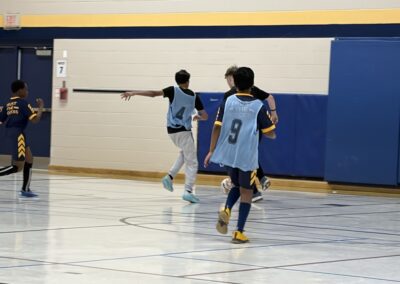 Young boys playing basketball indoors, one shooting the ball.