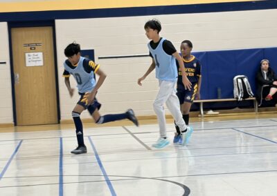 Two boys playing basketball in a gymnasium during a game.