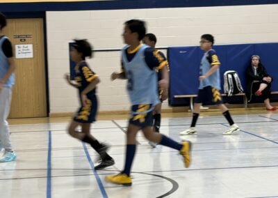Children playing indoor soccer in a gymnasium.