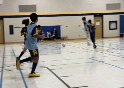 Children playing soccer indoors in a gymnasium.