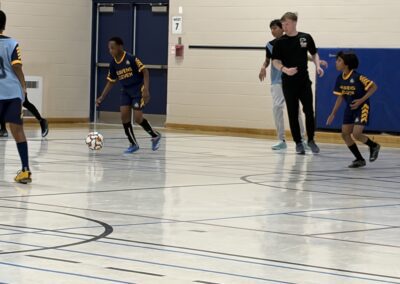 Indoor soccer game with young players in action on the court.