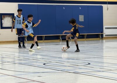 Two young boys playing indoor soccer, one controlling the ball.