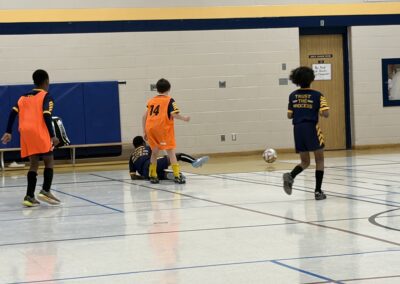 Children playing indoor soccer in a gymnasium.