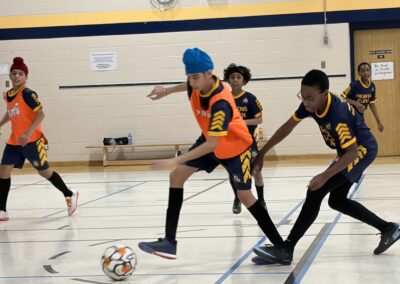Kids playing indoor soccer, focused on the ball.