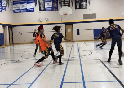 Kids playing indoor soccer in a gymnasium.