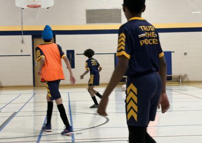 Youth basketball players in action on an indoor court.