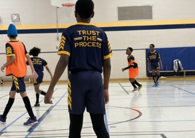 Youth basketball player wearing a 'Trust the Process' jersey on an indoor court.