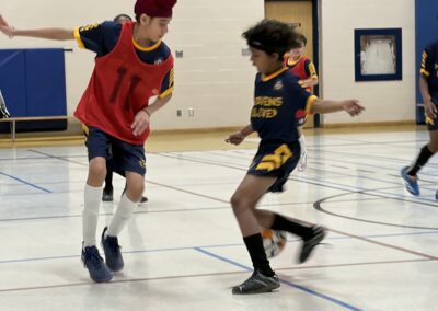Two boys compete in an indoor soccer game.
