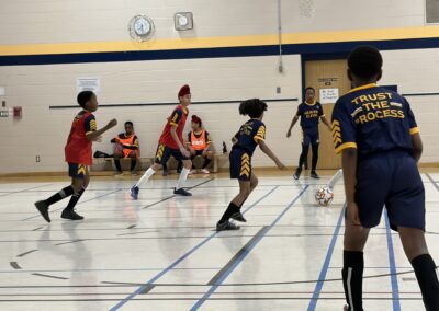 Youth volleyball game in progress with players ready at the net.
