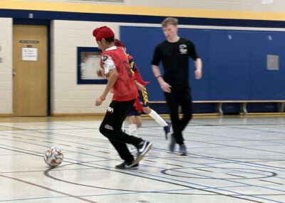 Two boys playing indoor soccer in a gymnasium.