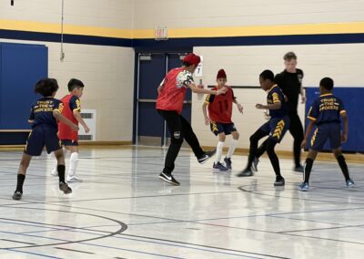 Kids playing indoor soccer in a gymnasium.