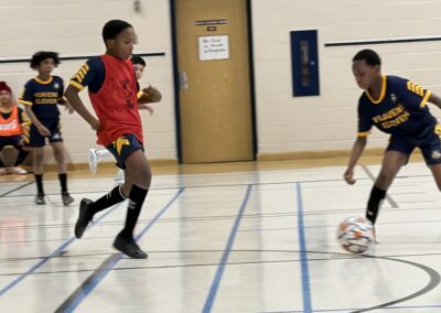 Indoor soccer match with players in action on the court.