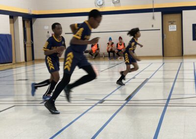 Young athletes sprinting indoors during a race.