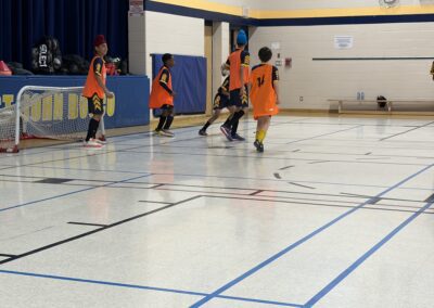 Kids playing indoor soccer in a gymnasium.