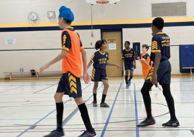 Youth basketball players in action during a game in a school gym.