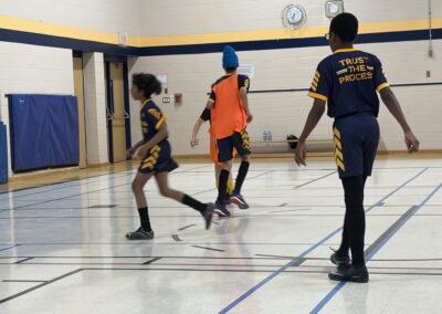 Youth playing indoor soccer in a gymnasium.