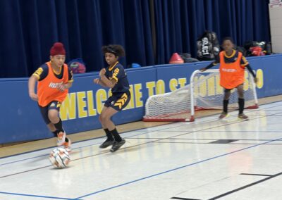 Youth basketball players compete in an indoor gym game.