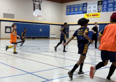 Young boys playing indoor basketball in a gymnasium.