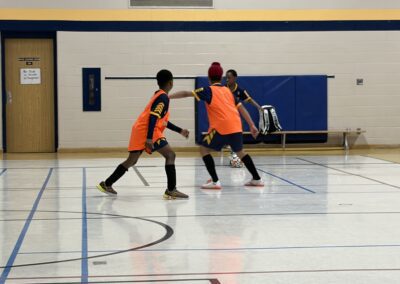 Two boys playing basketball in a gymnasium.