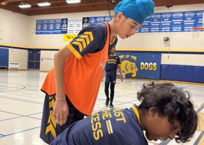 Two boys in sports uniforms practicing in a gymnasium.