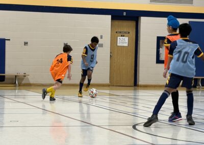 Kids playing indoor soccer, focused on the ball.