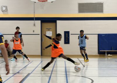 Children playing indoor soccer in a gymnasium.