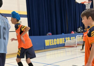 Two kids playing basketball in a gymnasium.