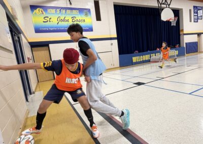 Two boys playing basketball defense and offense in a gym.